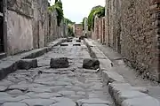 ポンペイの街路(の遺跡)。車道と歩道が分離され、歩行者の安全に配慮されている。飛石状のものは横断歩道で、馬車や荷車の車輪は通し、人は雨天でも足を水溜りで濡らさず道を渡れる。