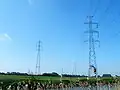 ベルギー・オースト＝フランデレン州・ダインゼ付近のエリアグループ保有の送電線。右が380KV送電線、左が150KV送電線