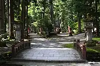 中宮祈願殿　境内手前にあるのが斎戒橋。左の道を行くと西本殿（立山大宮）と祈願殿、右の道を行くと東本殿（立山若宮）がある。中央付近奥に祈願殿の屋根が見える。