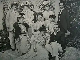 1901年以前。後3列目左からエドモン・ド・ポリニャック公、(ルーマニアボヤールの)ブランコヴァン公夫人、マルセル・プルースト、アンナ・ド･ノアイユの兄弟(ボヤールの)コンスタンタン・ブランコヴアヌ公ら。2列目中央がポリニャック公夫人ウィナレッタ・シンガー、右がアンナ・ド・ノアイユ。最前列の女性はアンナ・ド・ノアイユの2歳下の妹エレーヌ(エリザベットの弟アレクサンドル・カラマン＝シメイ伯夫人, 1878-1929年)