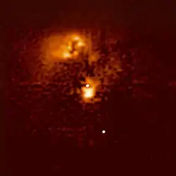 ハッブル宇宙望遠鏡によるクエーサーHE0450-2958の画像。クエーサーは画像の中心付近に見えるが、明らかなホスト銀河は見られない。画像の上部には、強く歪んだ星形成銀河がある。クエーサーの近くには、クエーサーからの放射によってイオン化しているガスの塊がある。右下にある点は、背景の恒星である。