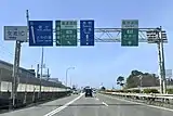 バイパス西行本線上のIC案内標識。左側の車線はランプウェイとなりIC高架橋部分は本線が減少する（2020年3月）