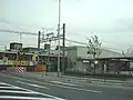 開業当初の駅舎（西口）。開業記念装飾の急行が通る（2003年4月25日）