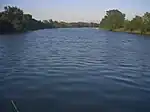 A middle-sized river flows placidly between banks covered in vegetation.