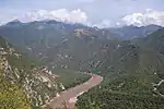 A muddy river winds along the bottom of a deep canyon.