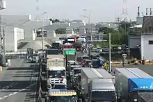 画像左:名二環着工前の富田IC付近(名古屋市中川区かの里付近)。専用部の用地は一般部中央に確保済であった。画像右:工事中の名古屋西JCT - 飛島JCT間(国道23号交差点付近 2017年5月)。港湾物流に関わる大型車の渋滞が著しいことから専用部の開通が期待された。