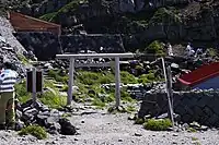 山頂御本社 鳥居新山登口側にある鳥居。付近では休憩する登山者の姿が見られる。