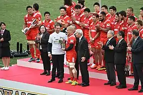 同左、18季ぶりの優勝で平尾誠二の遺影を手に表彰式に臨む前川鐘平（2018年12月15日撮影）