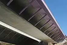 画像左 :中ノ合高架橋下り線側。着色部分が拡幅部分。画像右 :ストラット下部の受け皿（左画像）。当初から完成断面で建設された上り線側には受け皿はない（右画像）。