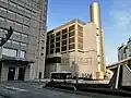 南側。円筒形の構造物の基部に交番。これに連なる窓のない建物が新宿地域冷暖房センター。手前にバス停とシャトルバス。