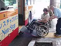 車椅子用のスロープ(ランプ)を使いバスに乗車している