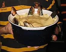 青い陶磁器で作るスターゲイジー・パイ、ショートクラスト・ペイストリーの蓋から突き出る6匹の魚が空を見上げる。