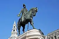 Photograph of a bronze statue with a man on horseback wearing a bicorn hat and military dress and who holds forth a scrolled sheaf of paper