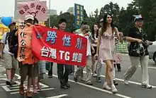 「私の性別は私が決める」などと書かれたプラカードを掲げた人々が道を更新する様子。