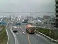 鶴川街道・稲城・矢野口方向から調布方向を臨む。下り車線は未完成の為、上り車線を分割供用している。2004年12月撮影。