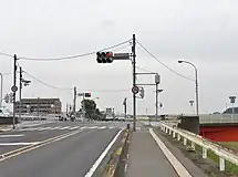 足利市・田中橋北交差点(起点、2015年6月)↑(東)方向が県道8号、→(南・田中橋)↓(西)が国道293号、←(北)が市道(至足利駅南口)である。