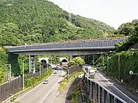 画像左 : 路線改良された大井松田IC - 御殿場IC間。左側の片側3車線道路が増設された上り線。右側は当初の往復4車線道路で、新上り線の開通を機に4車線全てが下り線となった。画像右 : 既存線との交差は2か所。画像はその内の吾妻山トンネルと都夫良野トンネル間に架かる新鍛冶屋敷橋。