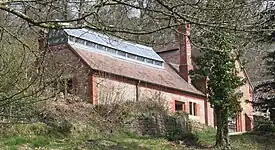 木立の奥にオレンジ色のレンガで作られた小屋が見える。小屋の屋根にはガラスの天窓や煙突が付いている