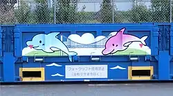 UM27A-48001 イルカのデザイン上に二箇所のフォーク挿しマークの赤色 ▼ 印が被っている。