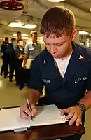 2004年6月7日、空母『ロナルド・レーガン』において、ノートブックに個人的なメッセージを寄せる乗組員たち。このノートブックは埋葬式で、同艦の艦長からナンシー・レーガンに贈呈された