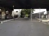 西から見た駅跡地の遠景。画面奥に向かって筑肥線の線路が延びていた。中央上のオーバーパスに残る、2本の黒い帯が煤煙の跡。