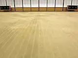 手織りカーペットの一種である緞通（だんつう）は、水面に雲が映りこんでいる情景を表現している。白線の中にある点々は、池の砂利を表している。